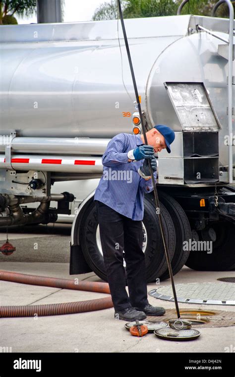 Using A Long Dip Stick A Gasoline Delivery Man Measures The Levels Using A Long Dip Stick A Gasoline Delivery Man Measures The Levels